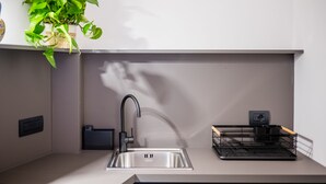 A modern kitchen with a stainless steel sink, a black faucet, and a black dish rack.