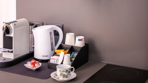 A kitchenette with a coffee maker, kettle, and tea set.