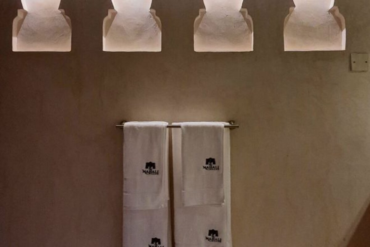 A bathroom with four wall-mounted towel racks and two towels hanging from a rack.