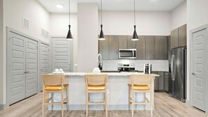 Una cocina moderna con una isla central, electrodomésticos de acero inoxidable y sillas de madera.