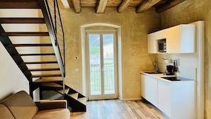 Une cuisine moderne avec un plancher en bois, un four à micro-ondes encastré et un escalier noir menant à un balcon.