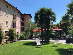 Relax in the serene courtyard, surrounded by lush greenery and shaded by elegant umbrellas.