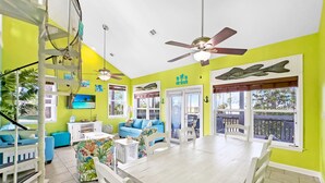 A bright room with a dining table, chairs, a blue sofa, and a ceiling fan.