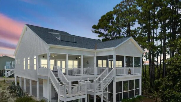 A two-story beach house with a covered porch and a staircase leading to the upper level.