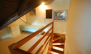A bedroom with a bunk bed, a dresser, and a painting on the wall.