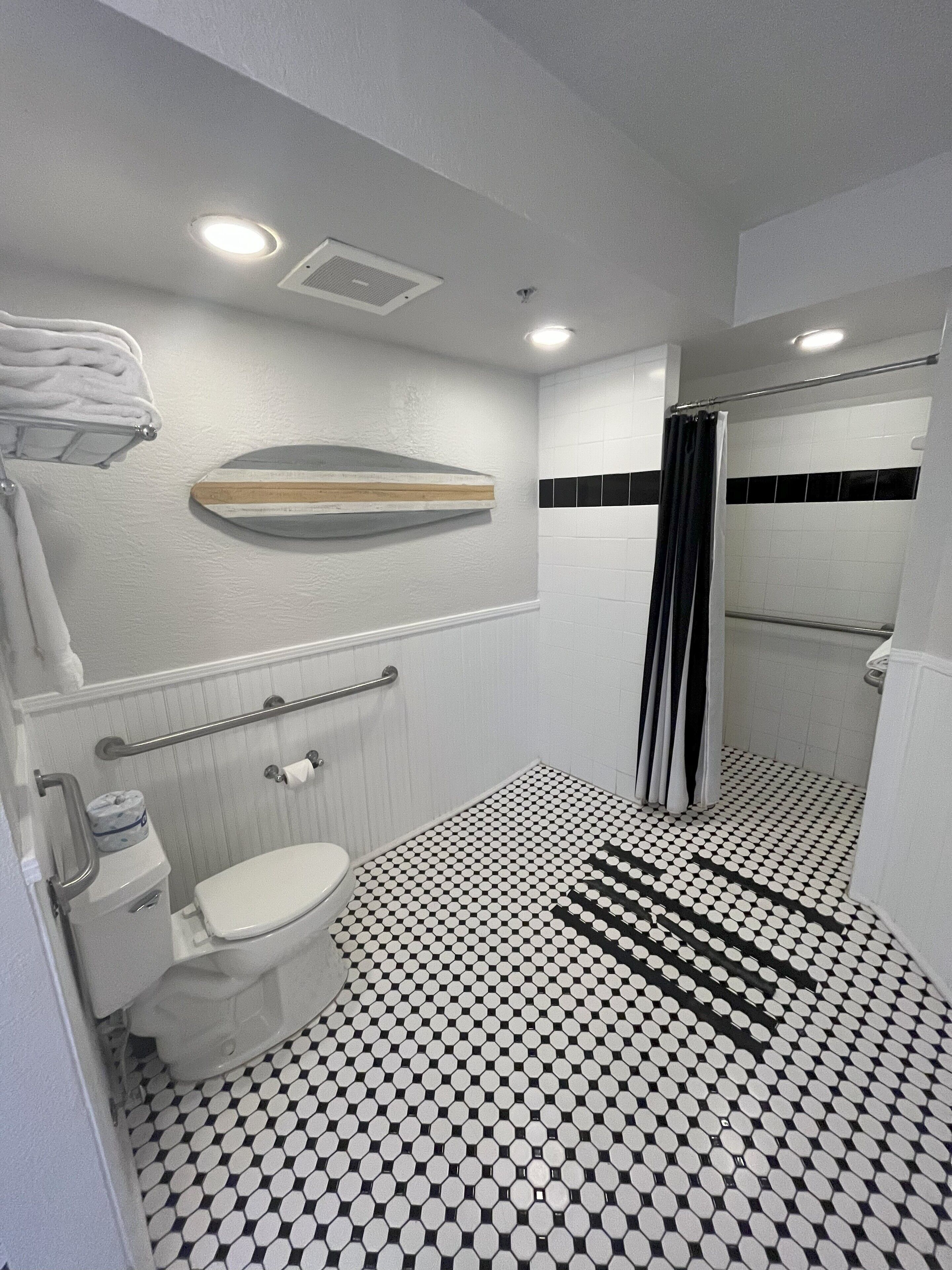 A bathroom with a toilet, a shower, and a sink.