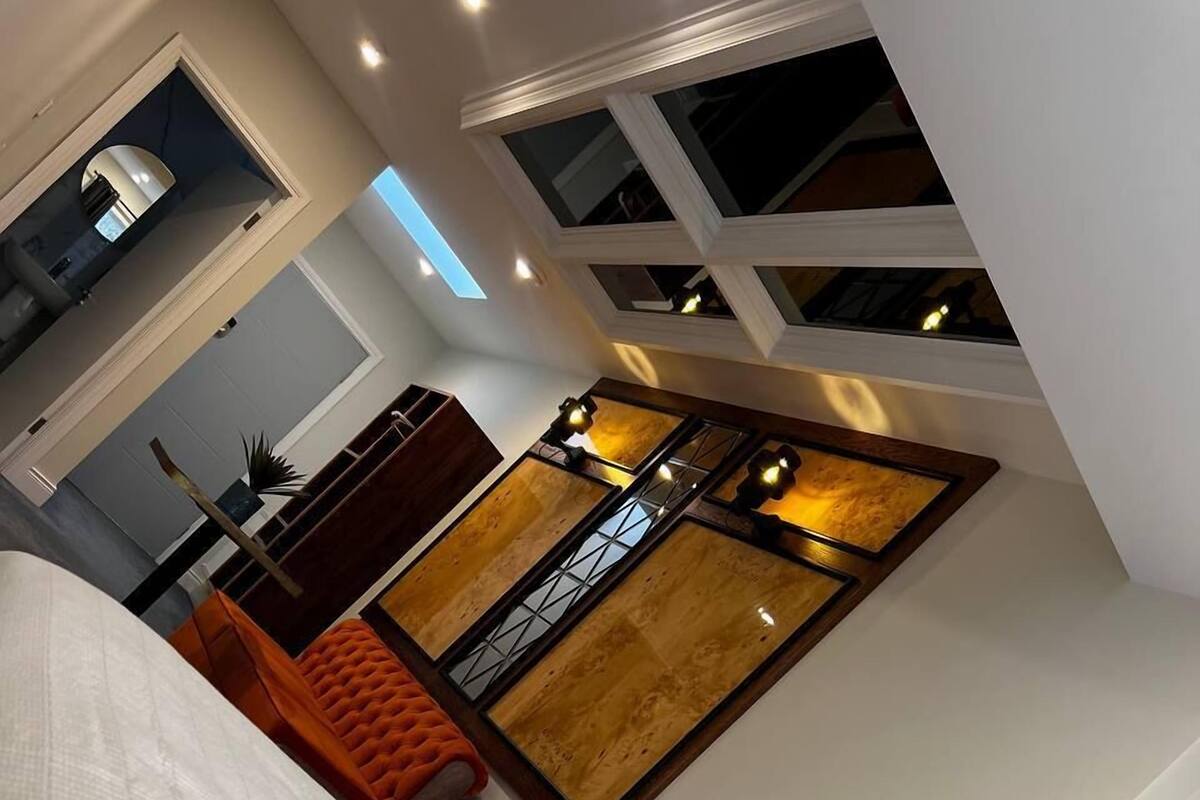 A hotel room with a large bed, a small desk, a chair, a window with a view, and a decorative wall piece.