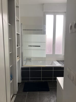 A modern bathroom with a glass shower enclosure, a white bathtub, and a window with frosted glass. - Maison Tout Confort Avec Jacuzzi (Corbie)