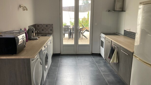 A compact kitchen with a washing machine, a microwave, and a refrigerator. - Maison Tout Confort Avec Jacuzzi (Corbie)