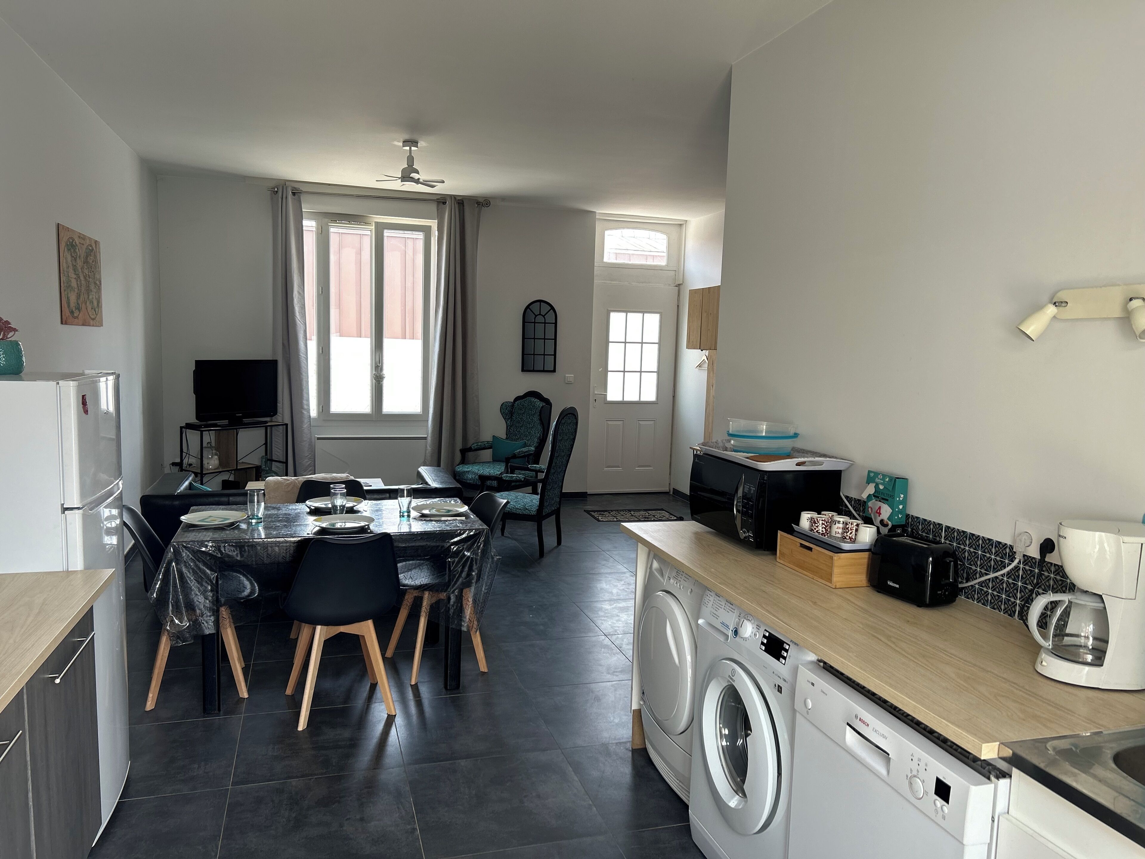Un espace de vie compact comprenant un coin repas, une cuisine et un espace buanderie.