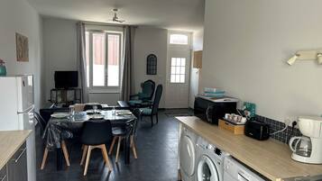 Un espace de vie compact comprenant un coin repas, une cuisine et un espace buanderie.