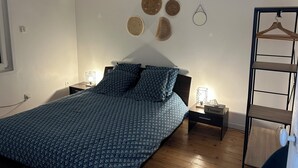 A bedroom with a bed, two bedside tables, a hanging light, a wall-mounted towel rack, and a wooden floor. - Maison Tout Confort Avec Jacuzzi (Corbie)