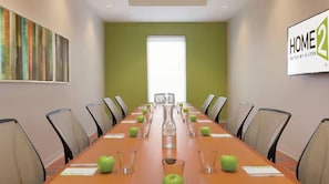 A conference room with a long table, chairs, and a large window. - Home2 Suites By Hilton Racine (Sturtevant)