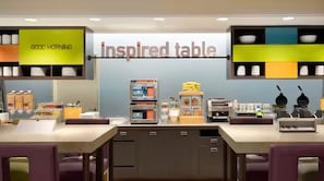 A cafe with a 'Good Morning' sign, a display of breakfast items, and a 'Inspired Table' sign. - Home2 Suites By Hilton Racine (Sturtevant)