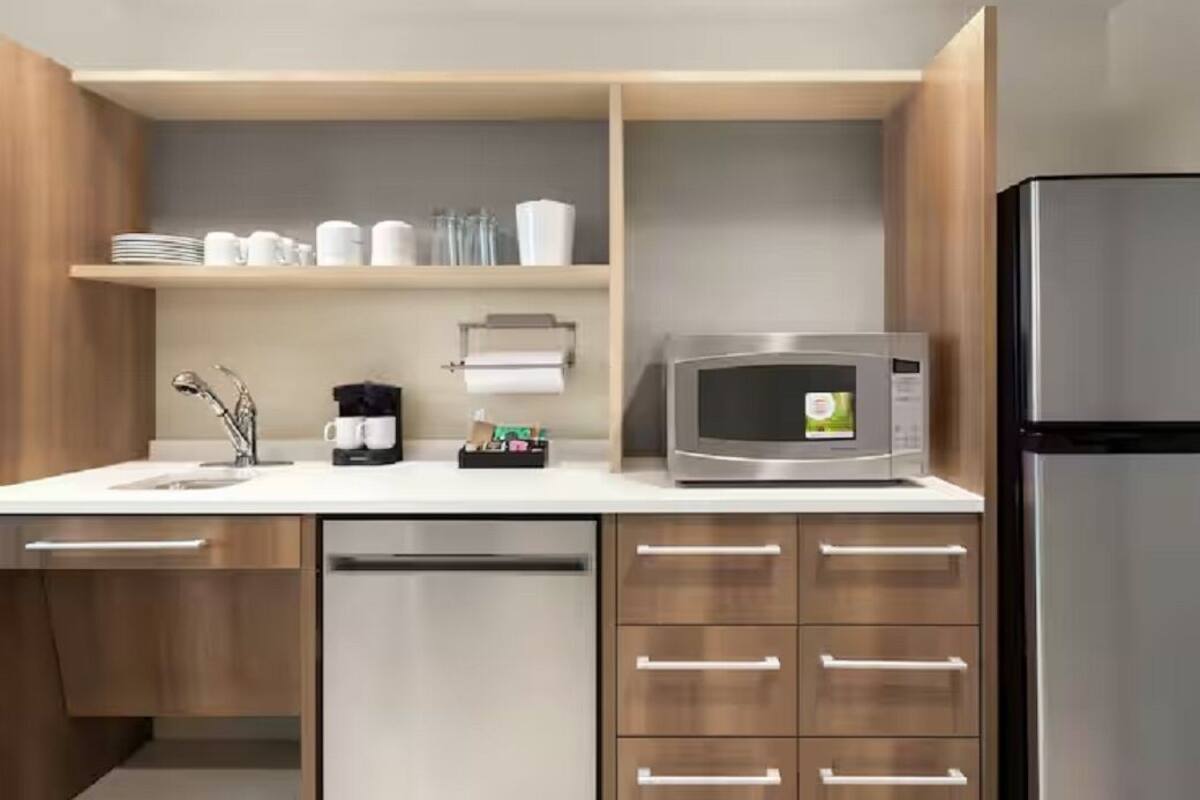A modern kitchen with a stainless steel refrigerator, a microwave, and a coffee maker on the counter.