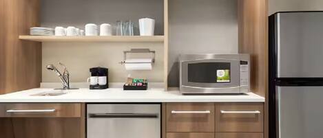 A modern kitchen with a stainless steel refrigerator, a microwave, and a coffee maker on the counter.