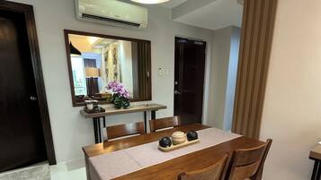 A dining area with a wooden table, chairs, a pendant light, and a mirror above the table.