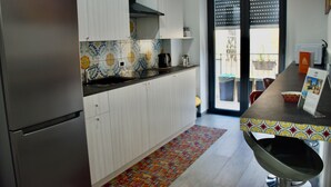 Une cuisine moderne avec des armoires blanches, un réfrigérateur en acier inoxydable, un pare-feu décoratif et un coin repas comprenant une table et des chaises.