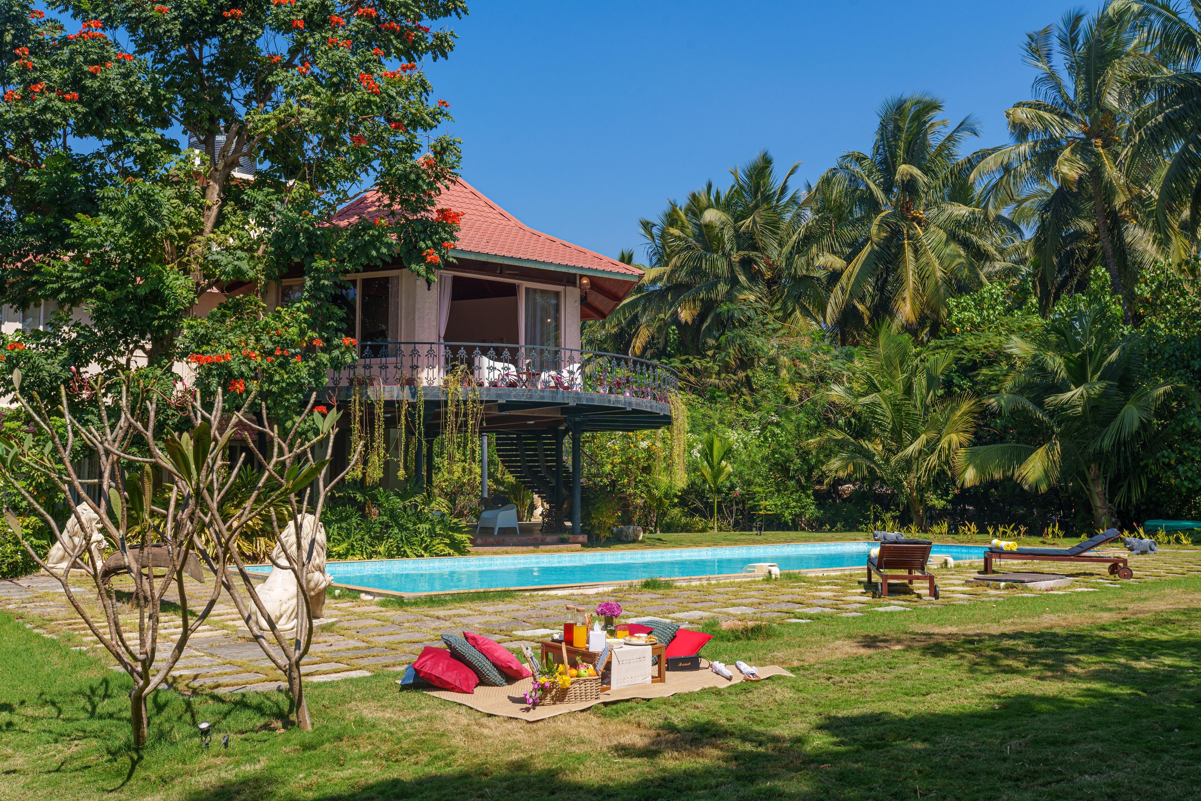 A house with a pool, outdoor furniture, and tropical vegetation.