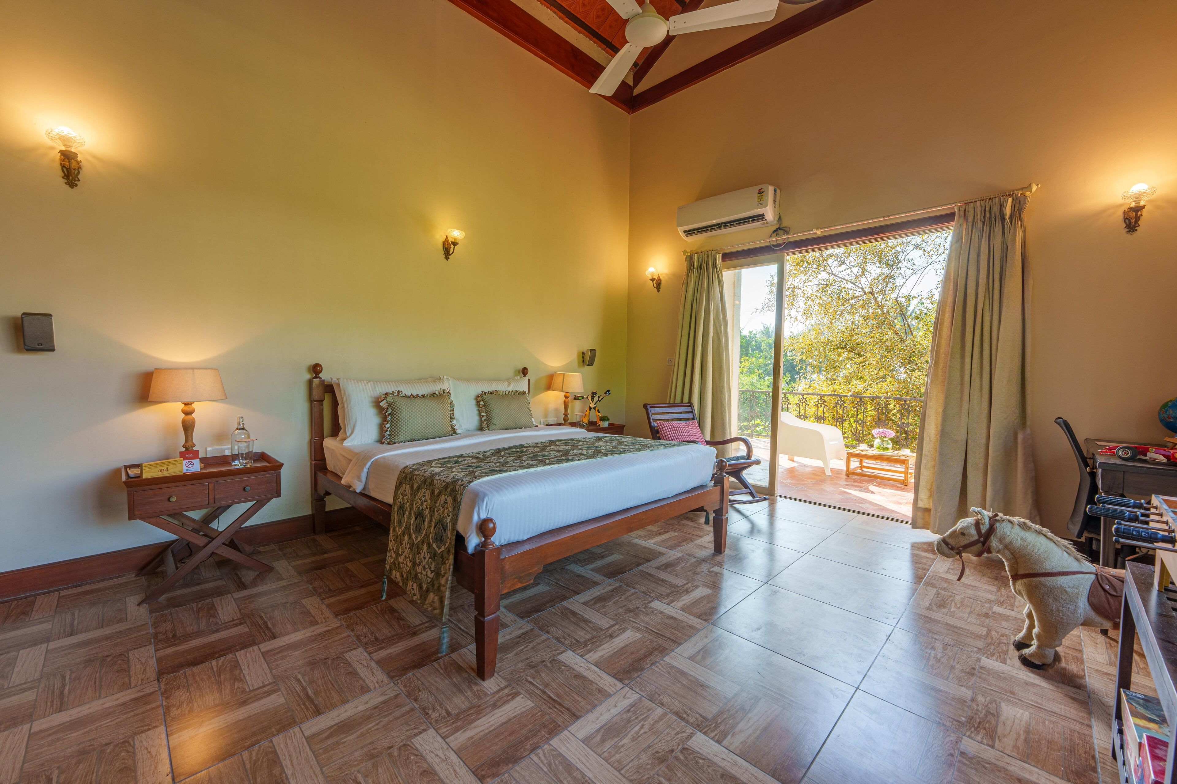 A bedroom with a wooden bed, bedside lamps, a nightstand, and a view of the outdoors.