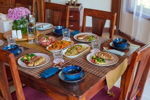 A dining table set with various dishes, glasses, and a vase of flowers. - Amã Stays & Trails Skyfall, Kashid (Murud)