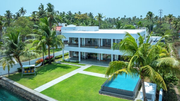 A modern two-story house with a swimming pool, surrounded by lush greenery and palm trees. - Amã Stays & Trails Anchorage Vypin, Cochin (Kochi)