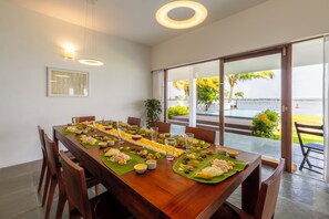 A dining table set with food and drinks, large windows, and a view of the outdoors. - Amã Stays & Trails Anchorage Vypin, Cochin (Kochi)