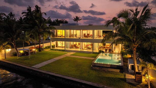 A modern two-story house with a swimming pool, surrounded by palm trees and a well-maintained lawn. - Amã Stays & Trails Anchorage Vypin, Cochin (Kochi)