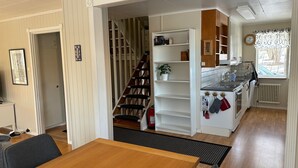 Een keuken met witte kasten, een houten trap en een eethoek met een houten tafel en stoelen.