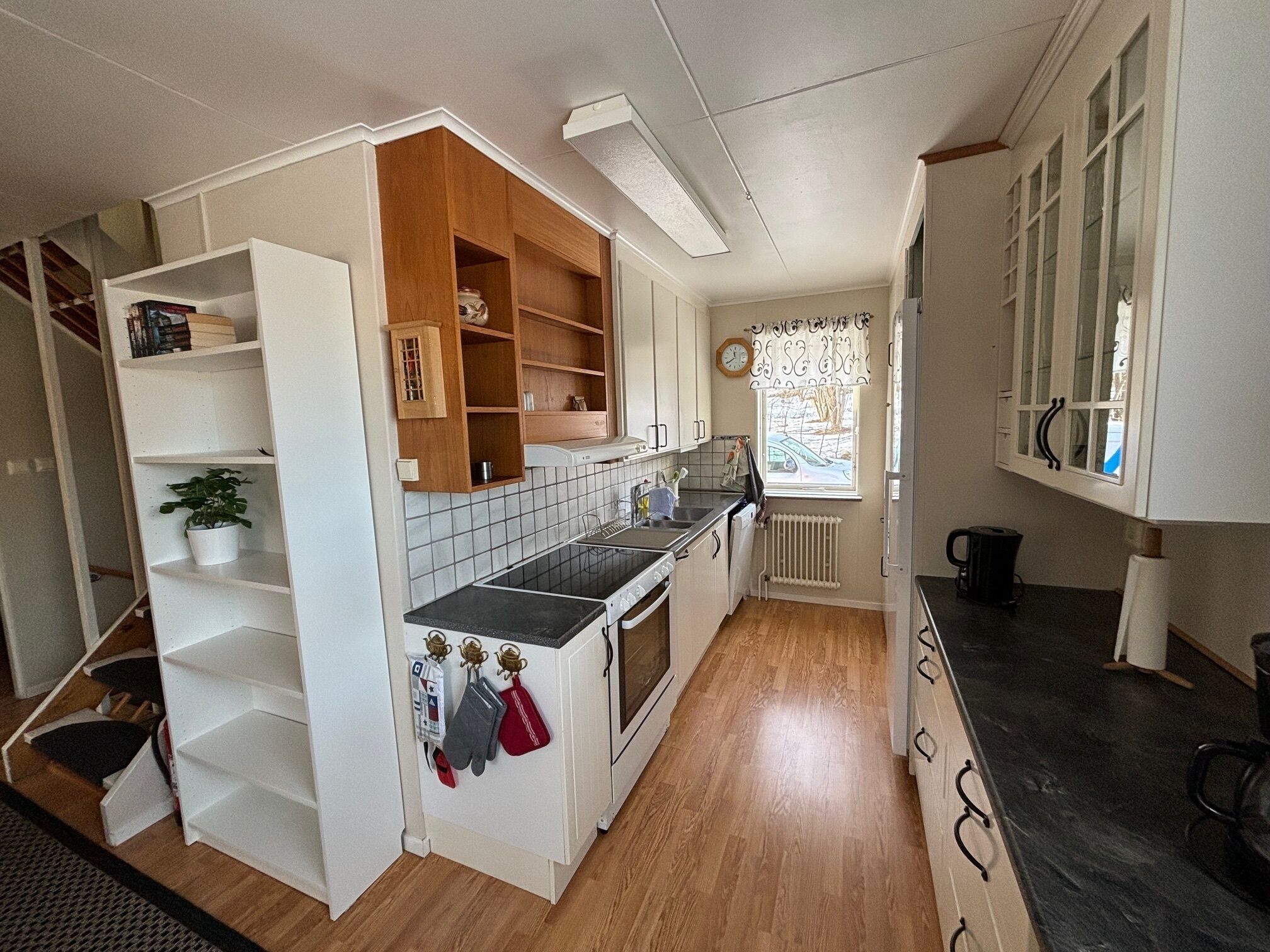 A kitchen with white cabinets, a black countertop, and wooden flooring.