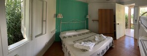 A bedroom with a bed, a green wall, a wooden wardrobe, and a window with greenery outside. - Villaggio Camping Formicoli (Ricadi)