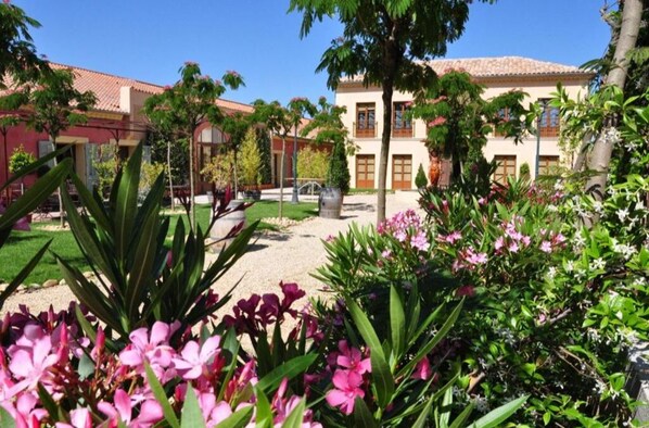 Traditional home surrounded by lush gardens and mature trees.