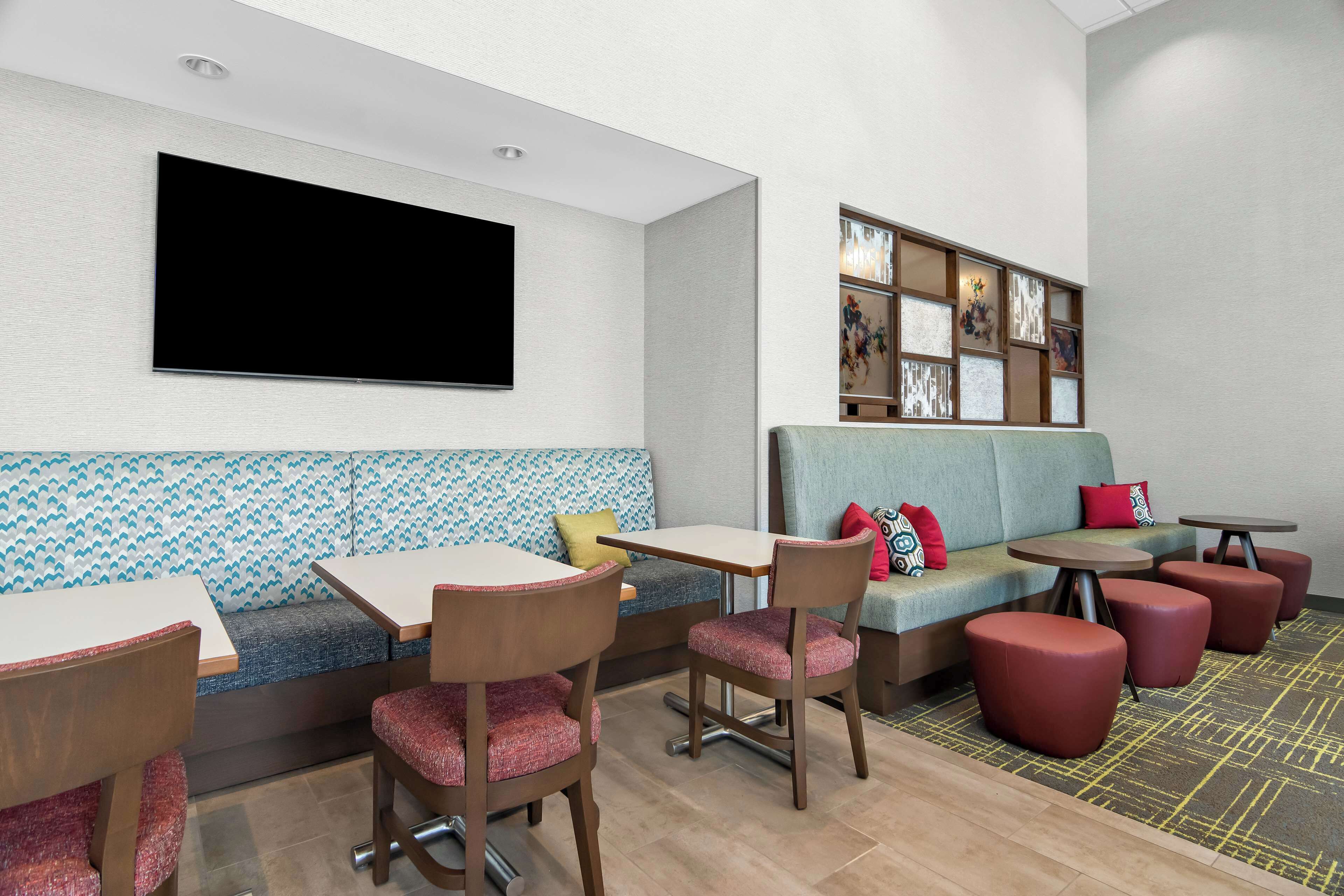 A modern lounge area with a sofa, chairs, tables, and a flat-screen TV.