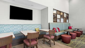 A modern lounge area with a sofa, chairs, tables, and a flat-screen TV.