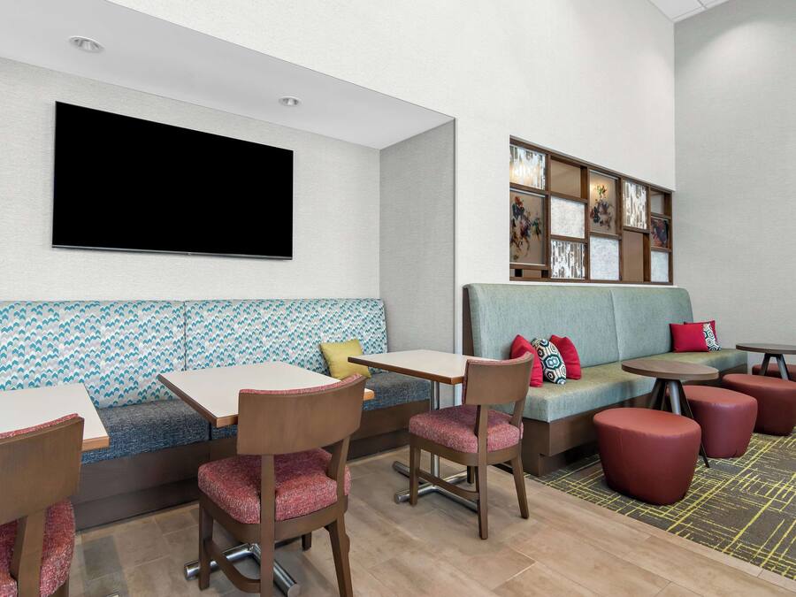A modern lounge area with a sofa, chairs, tables, and a flat-screen TV.