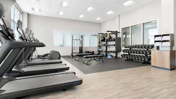 A gym with treadmills, weightlifting equipment, and dumbbells.