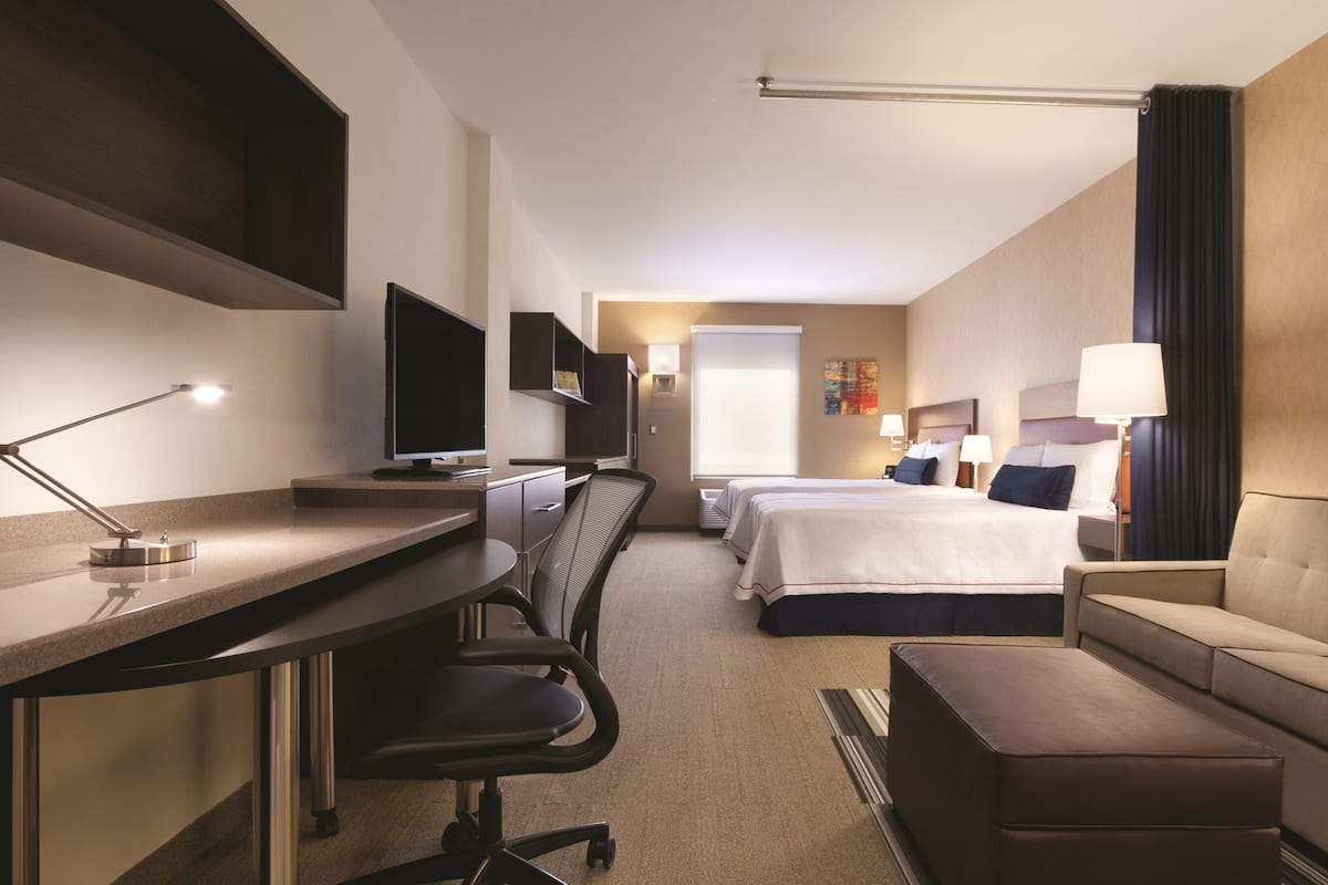 Ein Hotelzimmer mit Schreibtisch, zwei Betten, einer Couch und einem Fernseher.