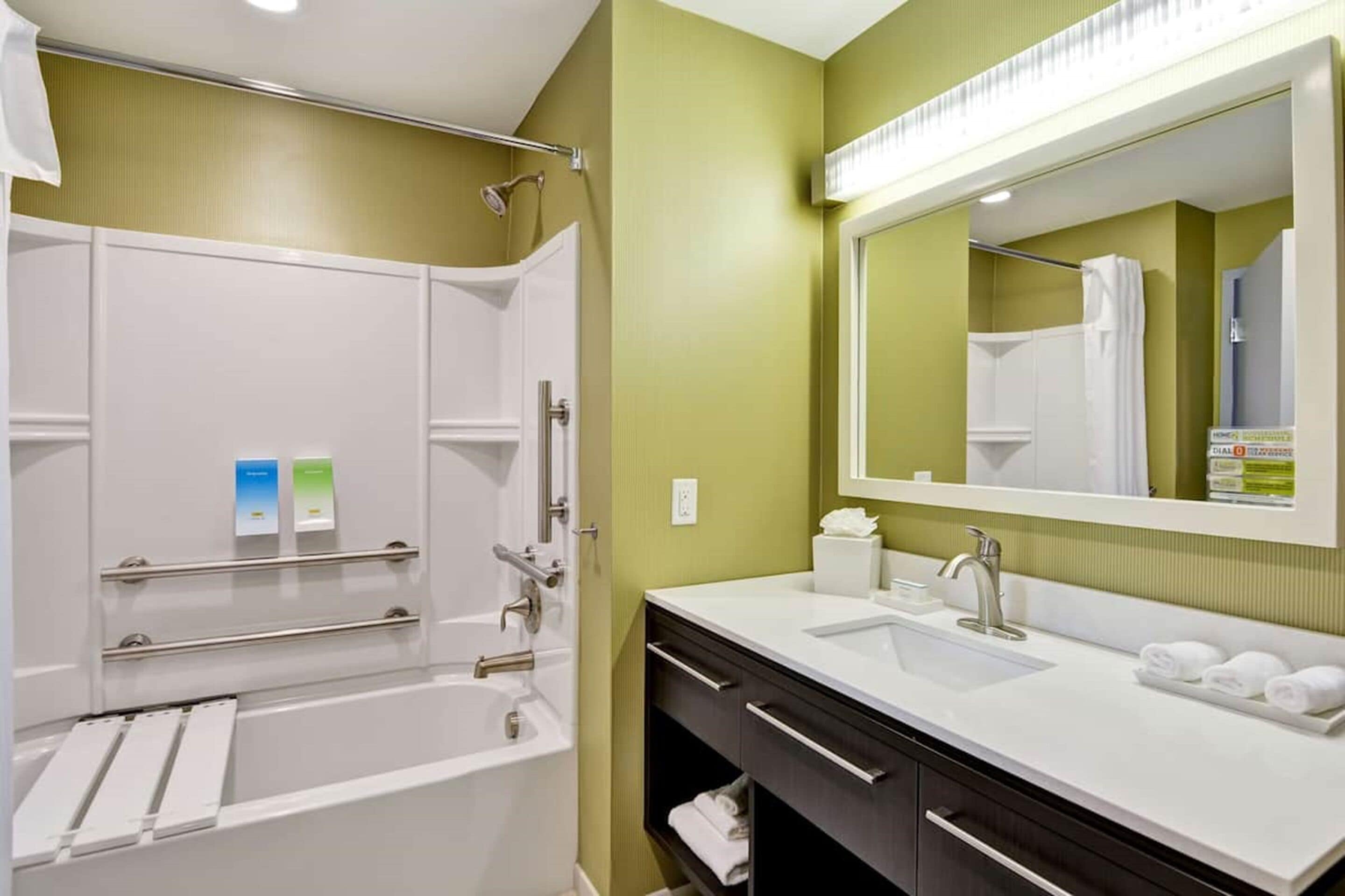 A modern bathroom with a bathtub, a sink, and a large mirror.