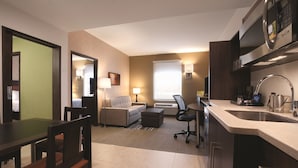 Een hotelkamer met een kitchenette, een slaapbank, een bureau en een eethoek.