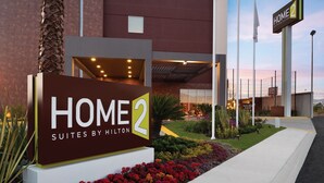 Een hotelentree met een bord waarop staat 'HOME 2 SUITES BY HILTON'.