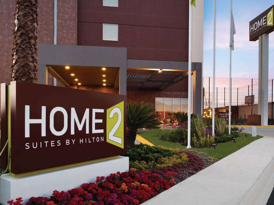 A hotel entrance with a sign reading "HOME 2 SUITES BY HILTON".