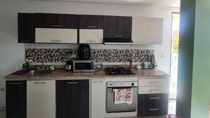 A modern kitchen with dark cabinets, a microwave, a gas stove, and a dishwasher. - Lindo y Acogedor Apartamento Cerca de Todo (Barranquilla)