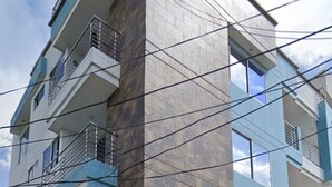 A multi-story residential building with balconies, a white fence, and a visible air conditioning unit. - Lindo y Acogedor Apartamento Cerca de Todo (Barranquilla)