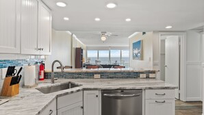 Una cocina moderna con armarios blancos, encimera de mármol y lavavajillas.