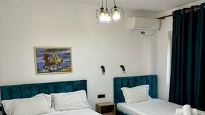 Habitación de hotel con dos camas, un cuadro de caballos, una lámpara de techo y un equipo de aire acondicionado.