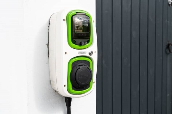 Un enchufe de pared con diseño verde y blanco, una pantalla digital y un botón redondo.