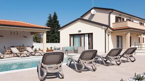 Ein modernes Gebäude mit Poolbereich, inklusive Liegestühlen und Essbereich.