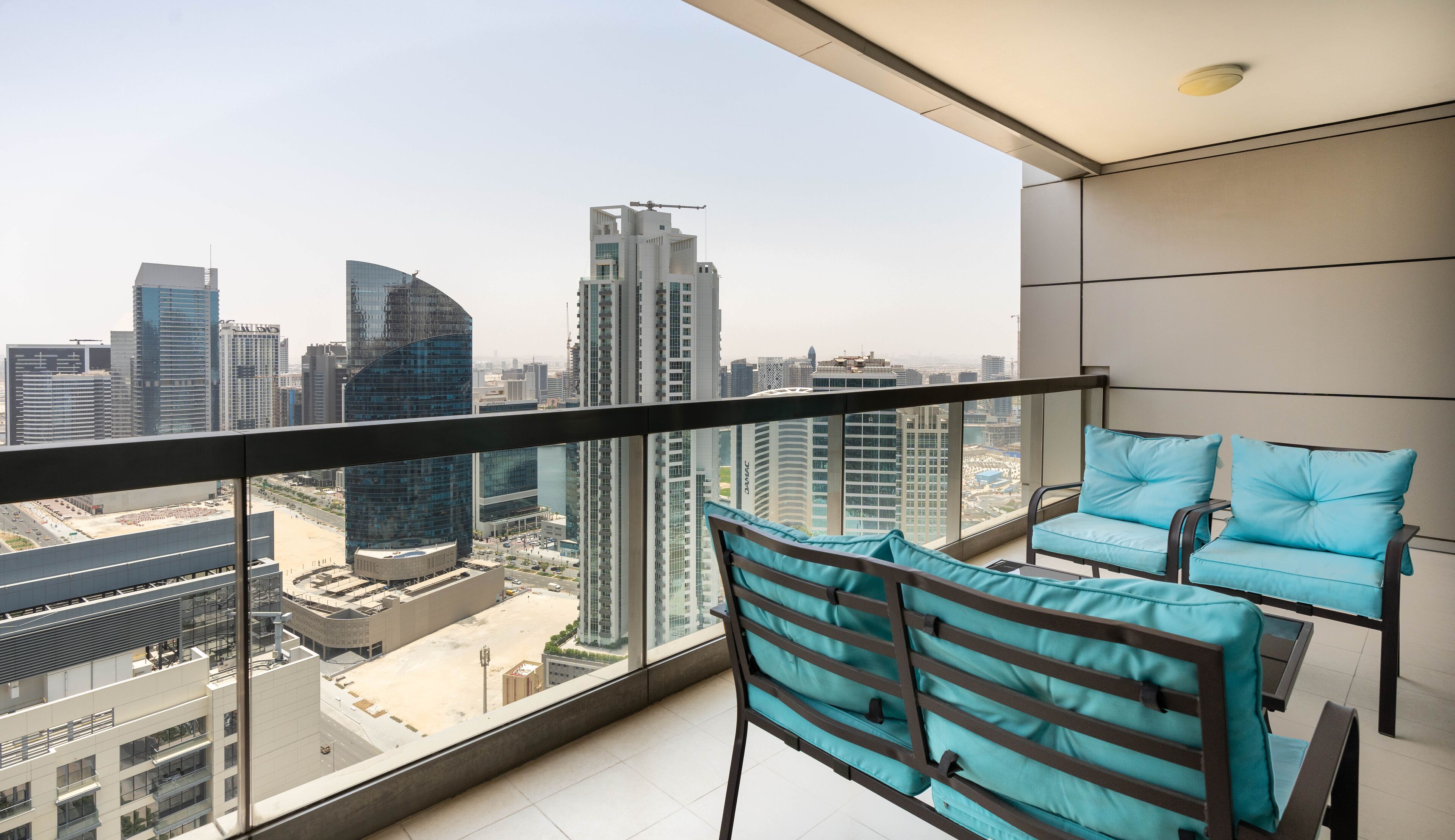 A balcony with a city view, two chairs, and a table.