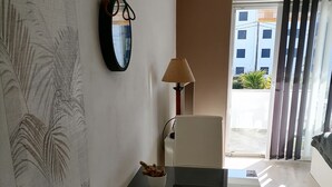Un salon moderne avec une table basse en verre noir, un canapé blanc et une lampe.