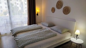 Un lit double avec une literie à motifs, une table de chevet avec une lampe et des œuvres d’art décoratives accrochées au mur.